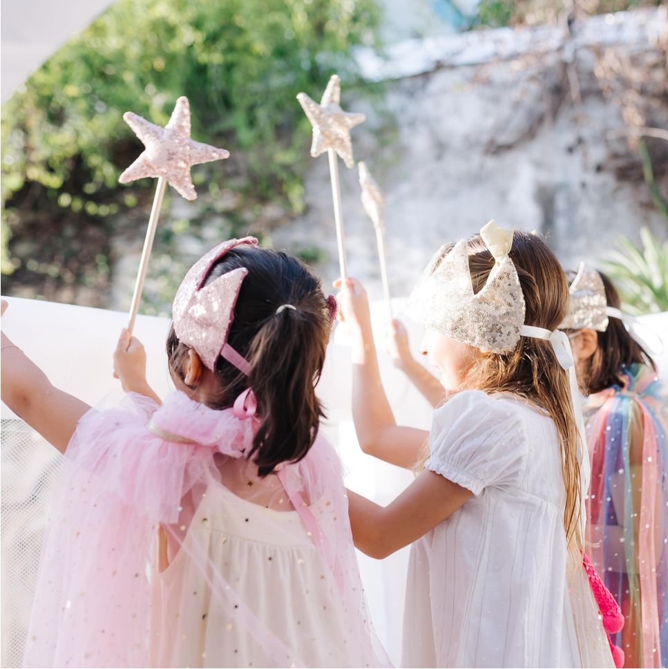Meninas fantasiadas com coroas e varinhas de estrela